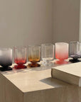 Sculpted Pedestal Glasses in frosted black and pink beside a book