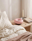 Pink Halo Touch Lamp on a bedside table beside a bed