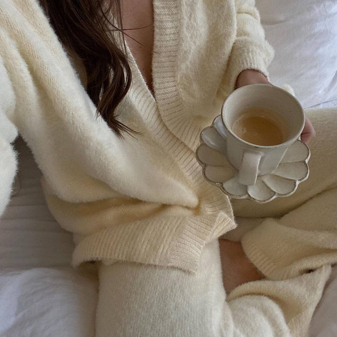 Woman in cozy sweater holding a delicate Rinka Collection mug filled with coffee, showcasing Japanese craftsmanship.
