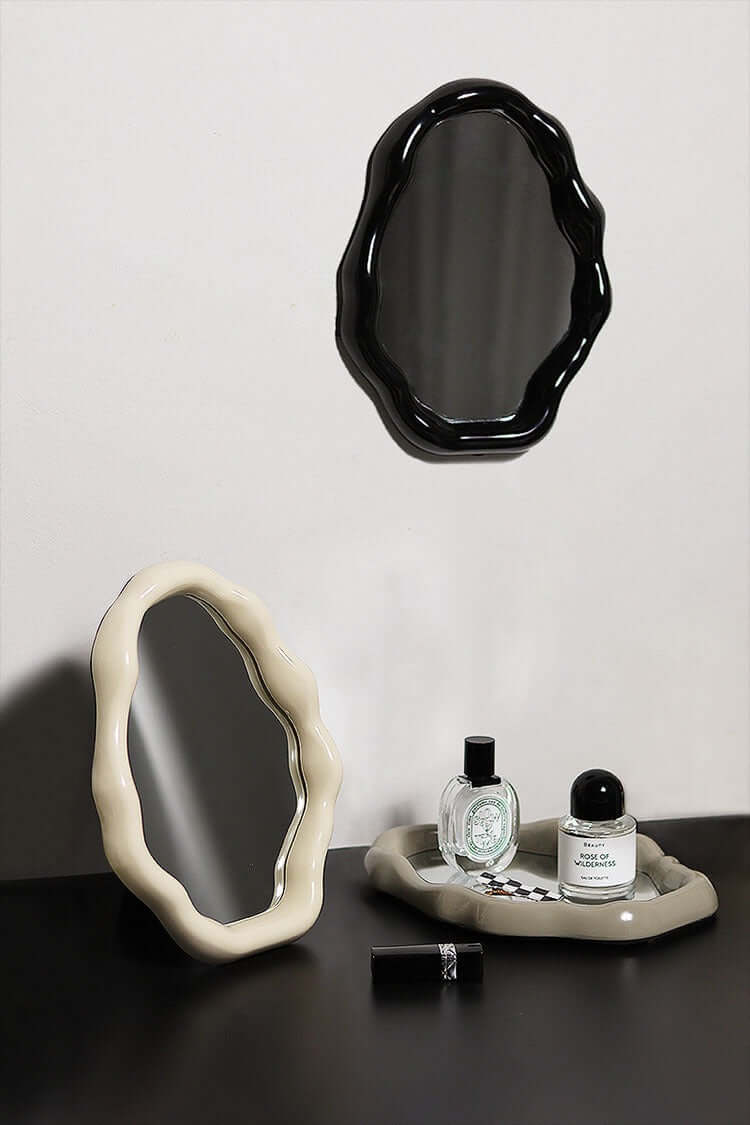 Nordic cloud-shaped vanity mirror set with black and white frames, perfumes, and lipstick on a dark surface.