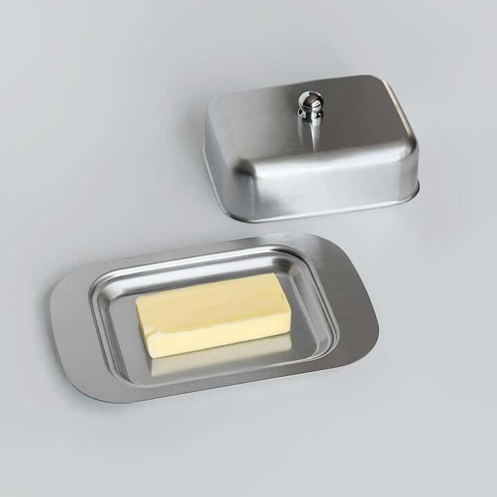 Stainless steel butter dish with lid, featuring a modern design and a stick of butter, by LoveÉcru.