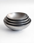 A set of four nested ceramic bowls with a matte, textured gray finish, photographed on a clean white background.