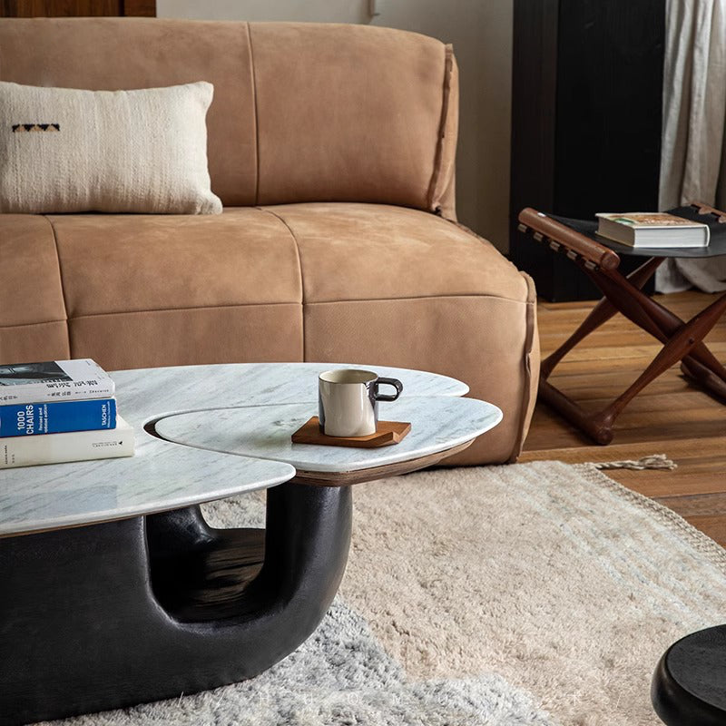 Contemporary Wabi-Sabi coffee table with wood and stone top, smooth curve base, in a modern living room setting with books and mug.