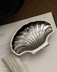 Vintage Shell-Shaped Silver Trinket Case on an open book