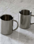 Double-layer glossy stainless steel cups on a marble surface, ideal for keeping beverages at the perfect temperature.