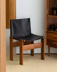Black leather seat dining chair with solid wood frame in a modern dining room setting.