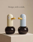 Butter cream duck-shaped automatic foam soap dispenser on a marble bathroom vanity — LoveÉcru" (vary per image: side profile, both colours, foam close-up, refill, in use).