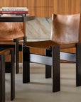 Modern dining chairs with brown leather seats and dark wooden frames in a stylish kitchen setting.