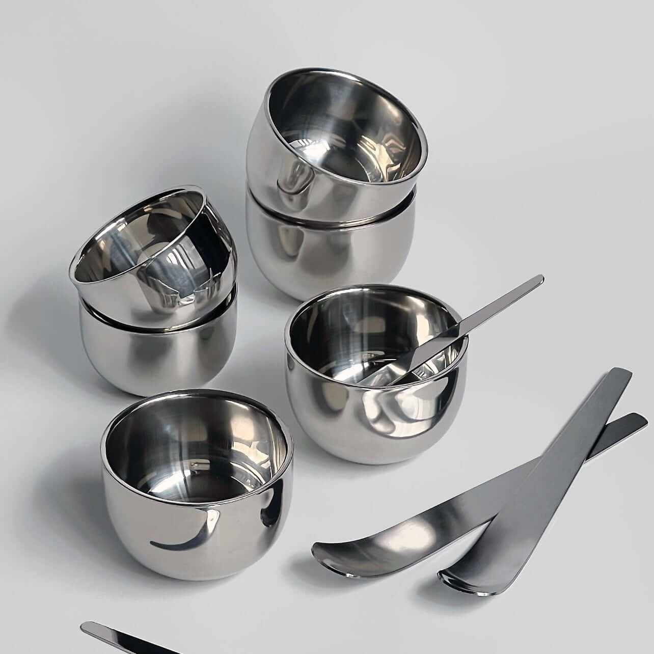 Stainless steel spherical cups set with sleek spoons, perfect for elegant dining and serving espresso or desserts.