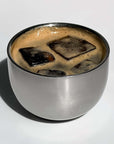 Stainless steel spherical cup with iced coffee inside, showcasing elegant design and double-walled insulation.