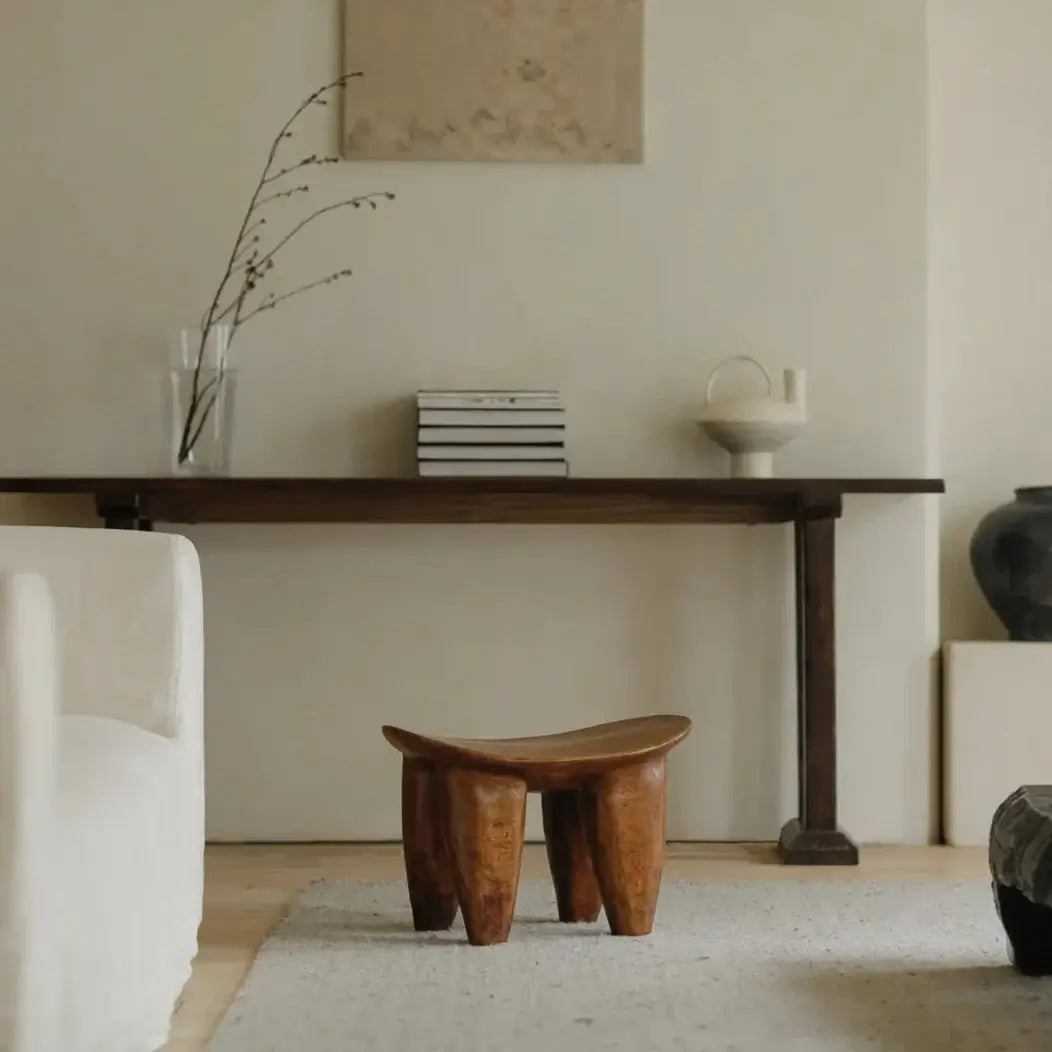 African Senufo wood milk stool in minimalist room setting, highlighting natural textures and retro finish.
