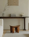 African Senufo wood milk stool in minimalist room setting, highlighting natural textures and retro finish.