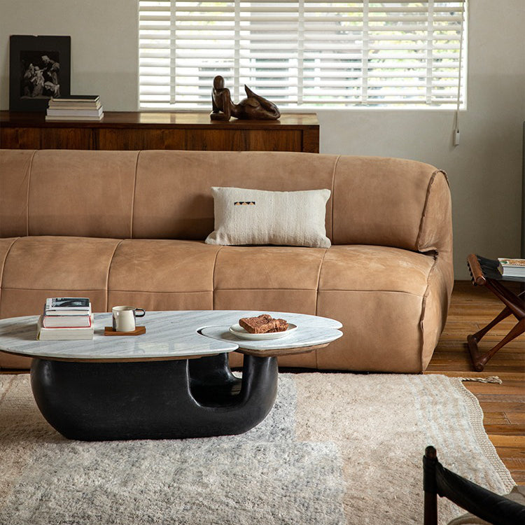 Modern living room with Wabi-Sabi coffee table featuring a wood and stone tabletop and unique curved base, in front of a beige sofa.