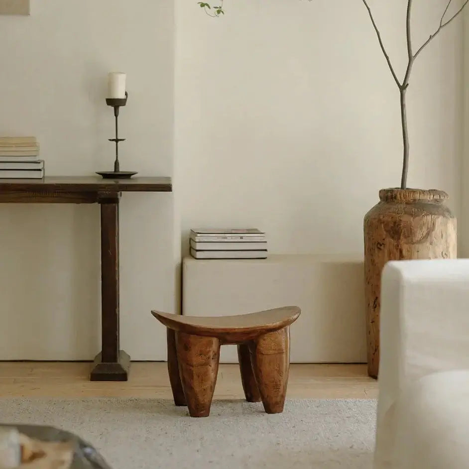 Handcrafted African Senufo wood milk stool in elegant interior, showcasing unique ethnic art and natural wood textures.