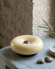 Cream Halo Touch Lamp on a stone plinth with pebbles