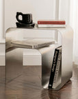 Minimalist stainless steel bedside table with books and mug, featuring modern design, perfect for elegant home decor.