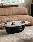 Modern Wabi-Sabi coffee table with wood and stone top, placed in a contemporary living room setting with a brown sofa.