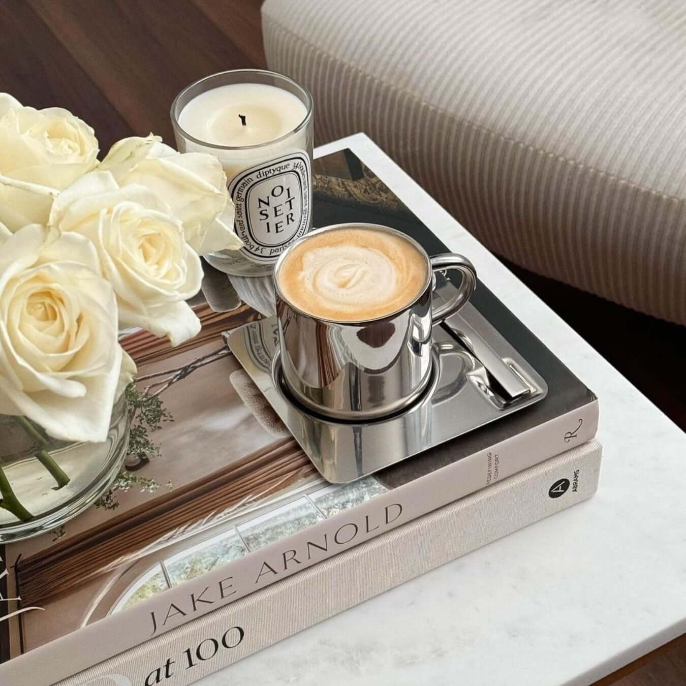 Elegant Venice Mirror Cup Set on books with roses and candle, featuring polished mirror finish for a luxurious coffee experience.