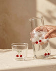 Hand pouring from the Cherry Glass Pitcher into a cherry cup