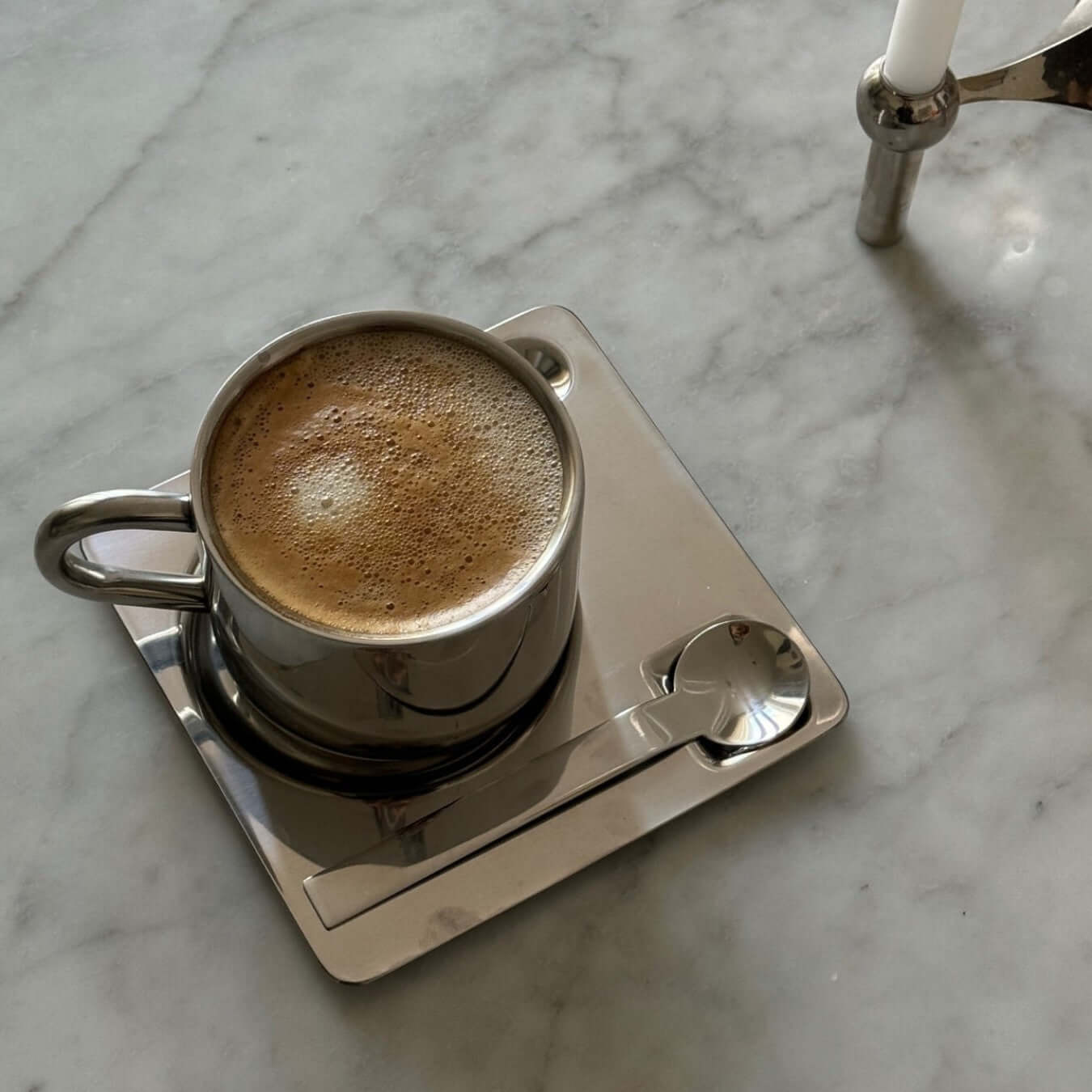Elegant Venice Mirror Cup Set with polished finish, featuring a coffee cup, saucer, and spoon on a marble surface.
