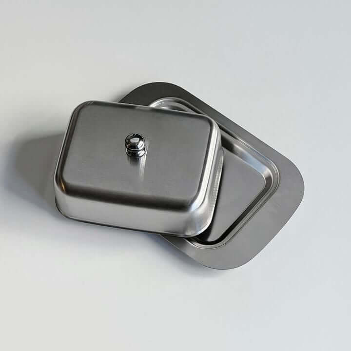 Stainless steel butter dish with lid on a flat surface.