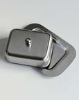 Stainless steel butter dish with lid on a flat surface.