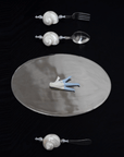 Shoreline Cutlery Set beside an oval steel plate on a black table