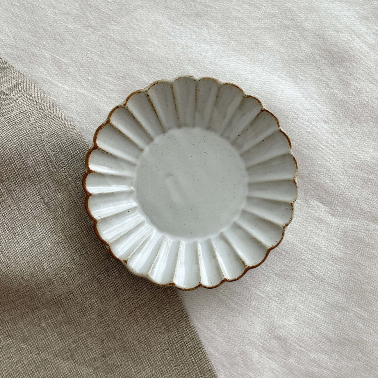 Elegant Marumitsu Barbarie Saucer with fluted design on neutral fabric background. High-quality ceramic tableware.