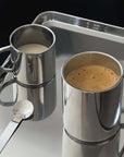Double-layer glossy stainless steel cups with coffee and milk on a metal tray, showcasing modern elegance and temperature control.