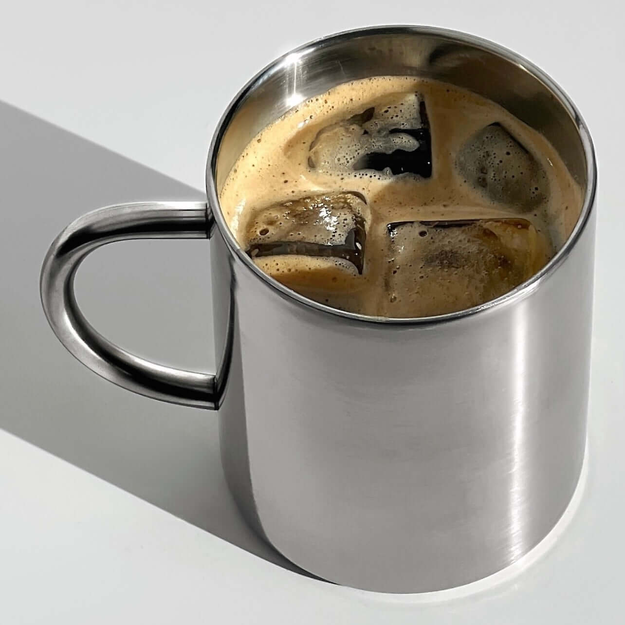 Stainless steel coffee mug from Milano Duo Set with iced coffee, showcasing elegant and functional design.