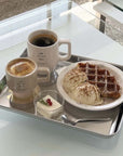 Stainless steel tray with coffee, waffles, and ice cream, showcasing minimalist design and elegance.