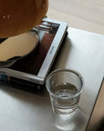 Minimalist Bauhaus Stainless Steel Side Table with books, a glass and a lamp on top
