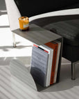Bauhaus Steel Accent Table & Magazine Holder beside a sofa with a candle on top