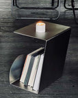Bauhaus Steel Accent Table with a candle on top and books in the rack