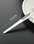 Minimalist dessert spoon with measurements of 12.2cm length and 1.5cm width displayed beside a scalloped plate.