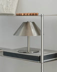 Atelier Halo Lamp on a black table beside a steel shelving unit