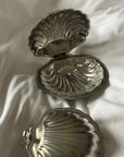 Clara Glass Shell Dish inside the open Vintage Metal Shell Box on a bed