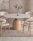 Elegant solid wood round table with minimalist Italian design, featuring a heavy base and four matching chairs in a modern dining room.