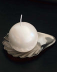 Dreamy Swing pearl-finish ball candle on a scalloped shell plate