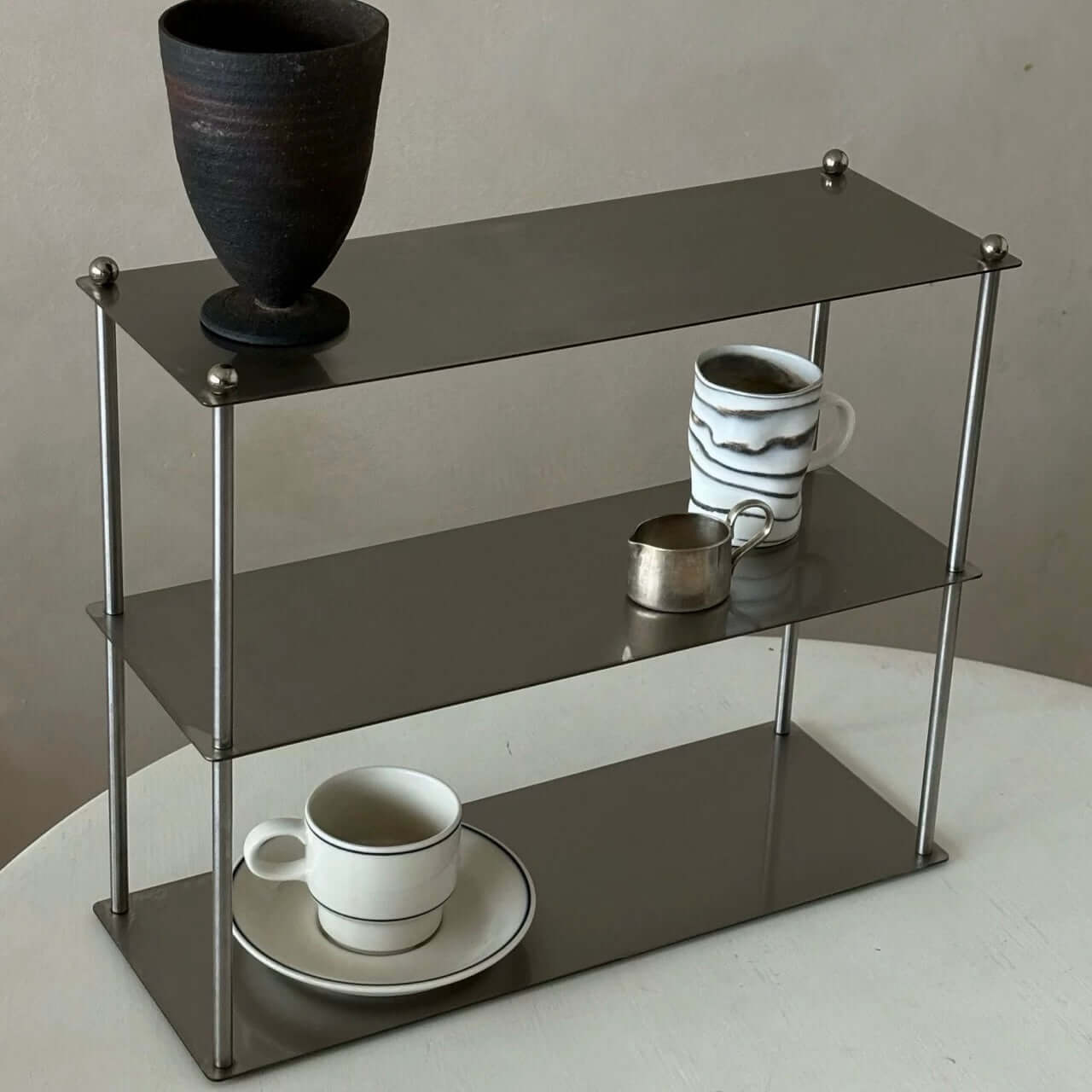 "Aira Stainless Shelf displaying cups and decorative vase, modern minimalist design, brushed 304 stainless steel finish"