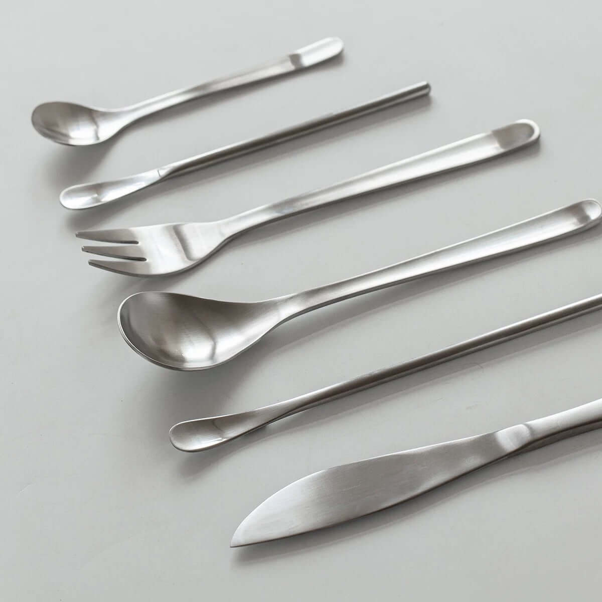 Japanese Retro Stainless Steel Cutlery Set with seven elegant brushed pieces including spoons, fork, and knife on a white background.