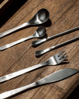 Japanese retro stainless steel cutlery set on wooden surface, featuring spoons, fork, and knife for elegant dining.