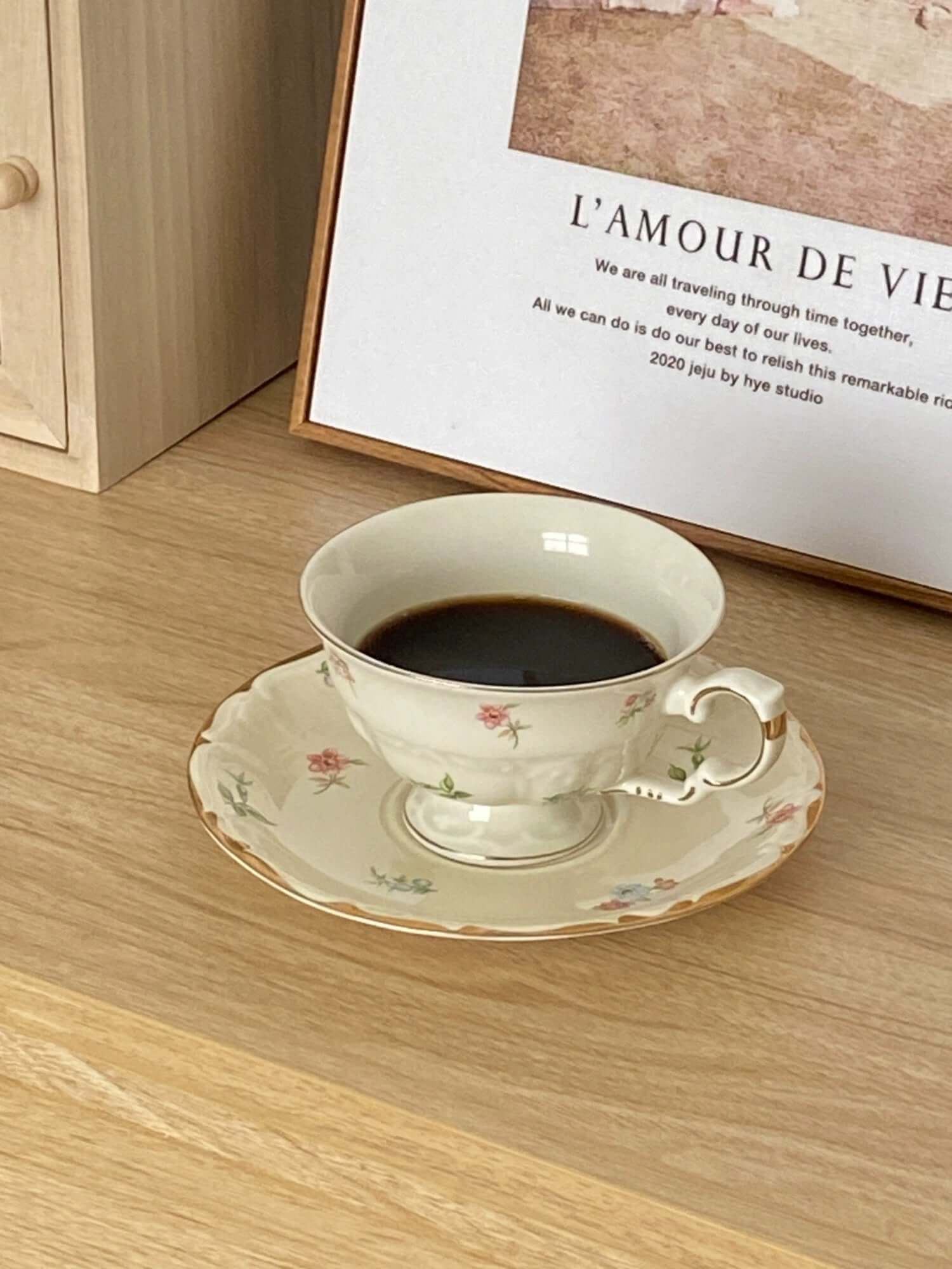 Retro French Blossom cup and saucer set with coffee, featuring chic floral design on a wooden table.