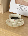 Retro French Blossom cup and saucer set with coffee, featuring chic floral design on a wooden table.