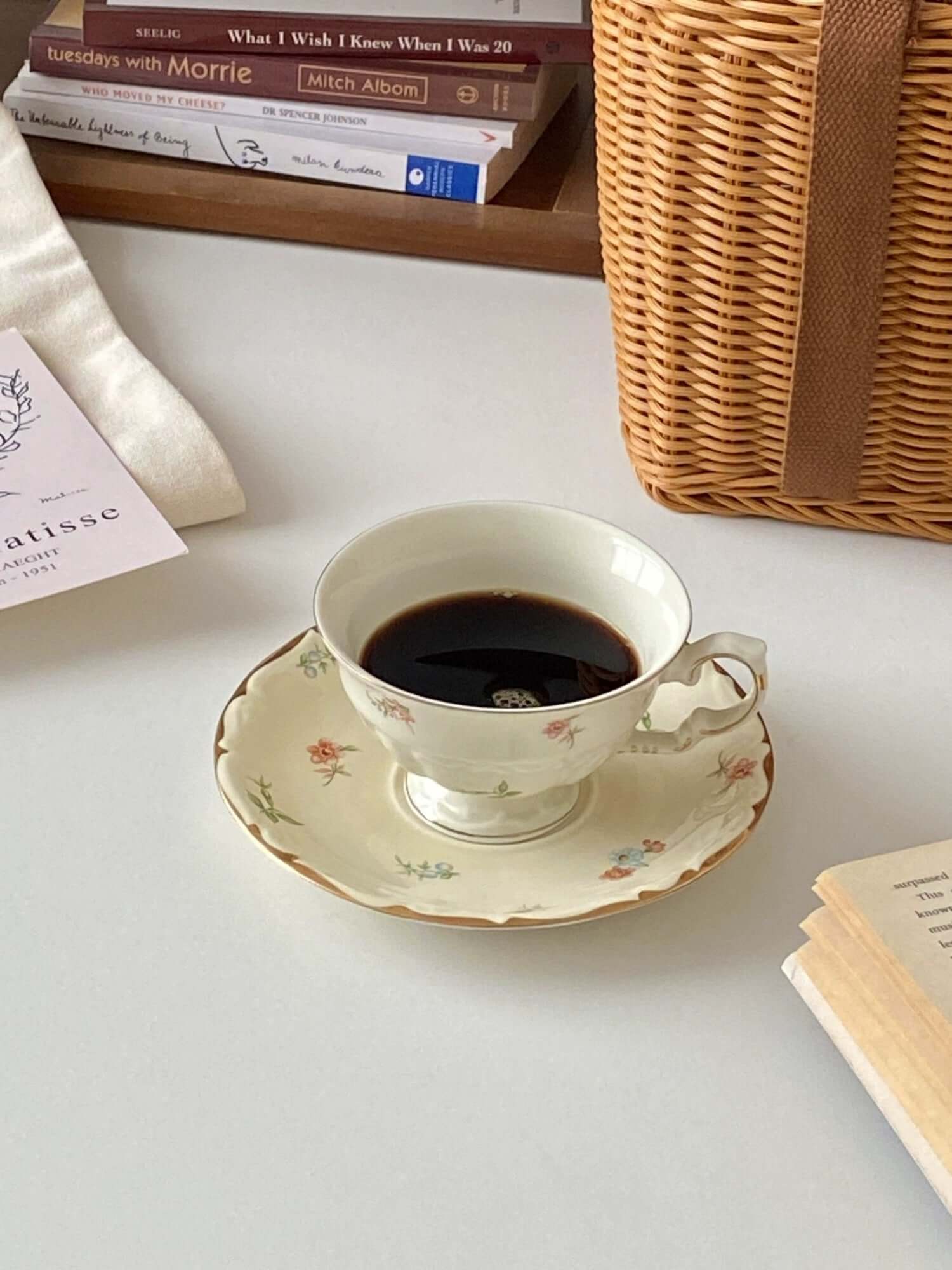 Retro French Blossom cup and saucer set on a table with a book and wicker basket, showcasing vintage charm and elegant design.