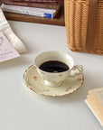 Retro French Blossom cup and saucer set on a table with a book and wicker basket, showcasing vintage charm and elegant design.