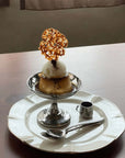 Elegant dessert cup featuring ice cream with a caramel decoration, served on a stainless steel dish with a spoon and mini pitcher.