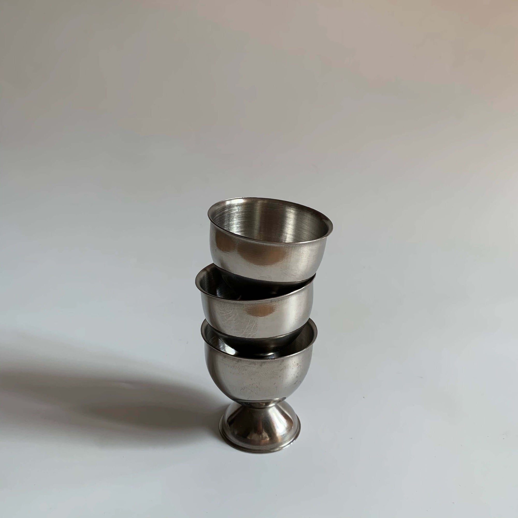 Stack of three stainless steel egg holders with matte finish, showcasing durable and stylish design for kitchen decor.