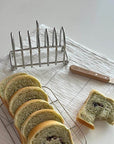 Elegant stainless steel toast holder with mirror finish, featuring six slices of bread on a table with a knife nearby.