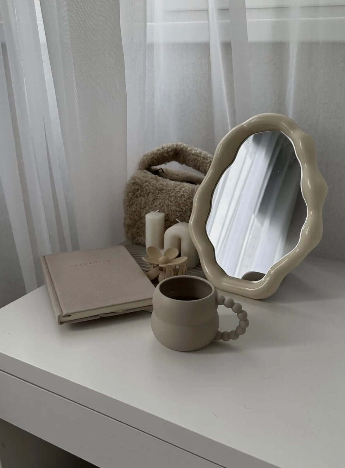 Nordic cloud-shaped vanity mirror on a table with book, cup, and candles, enhancing home decor with modern elegance and free shipping.
